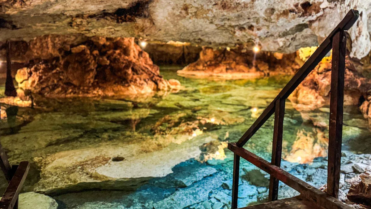 A climber rappelling on a rope down into a stalactite cavern cenote on a sacred cenotes tour near Tulum