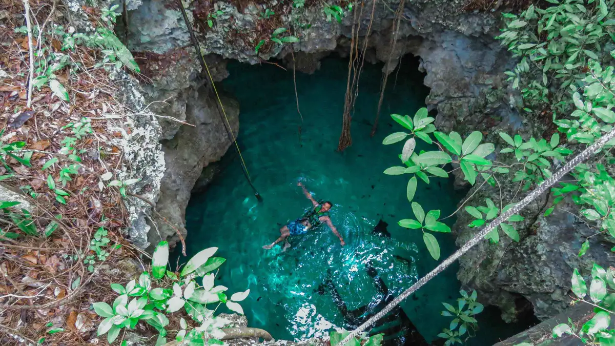 A snorkeller with a waterproof lamp in the Taak Bi Ha cave cenote on a three cenote tour from Tulum